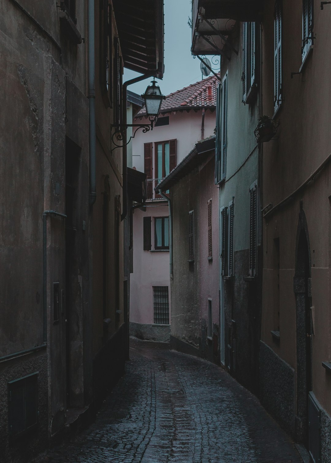Foggy cobblestone alley in an old European town at night with a single streetlamp